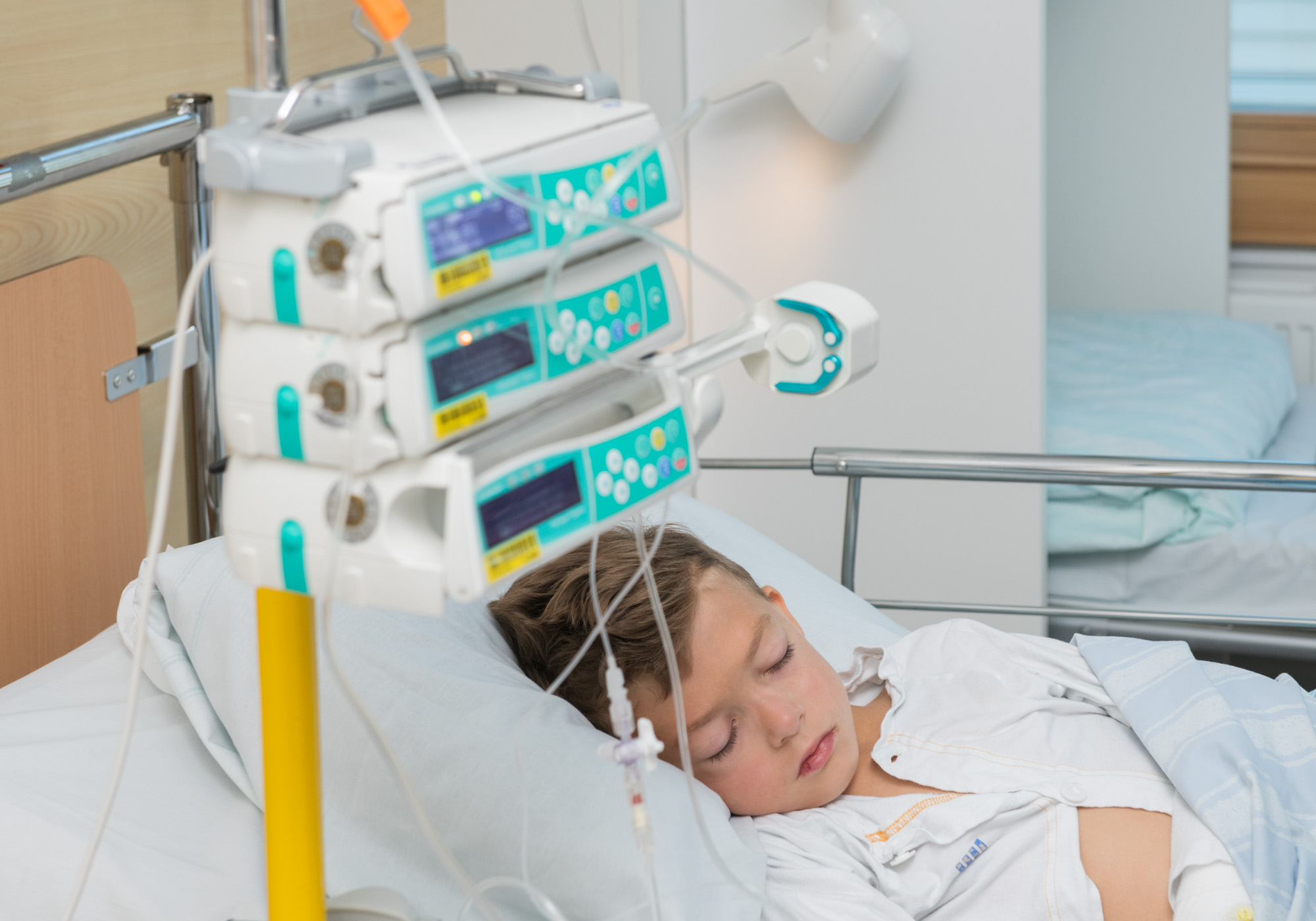 Boy in bed with infusion pumps next to him.