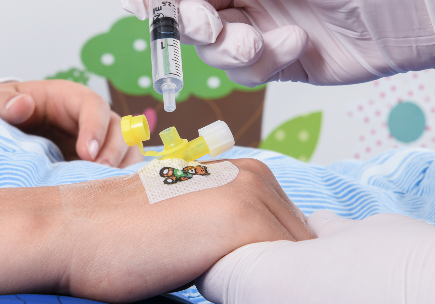Lollo’s hands injecting something from a transparent syringe into the yellow thing.