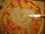 A half-eaten pizza and a knife in a pizza box