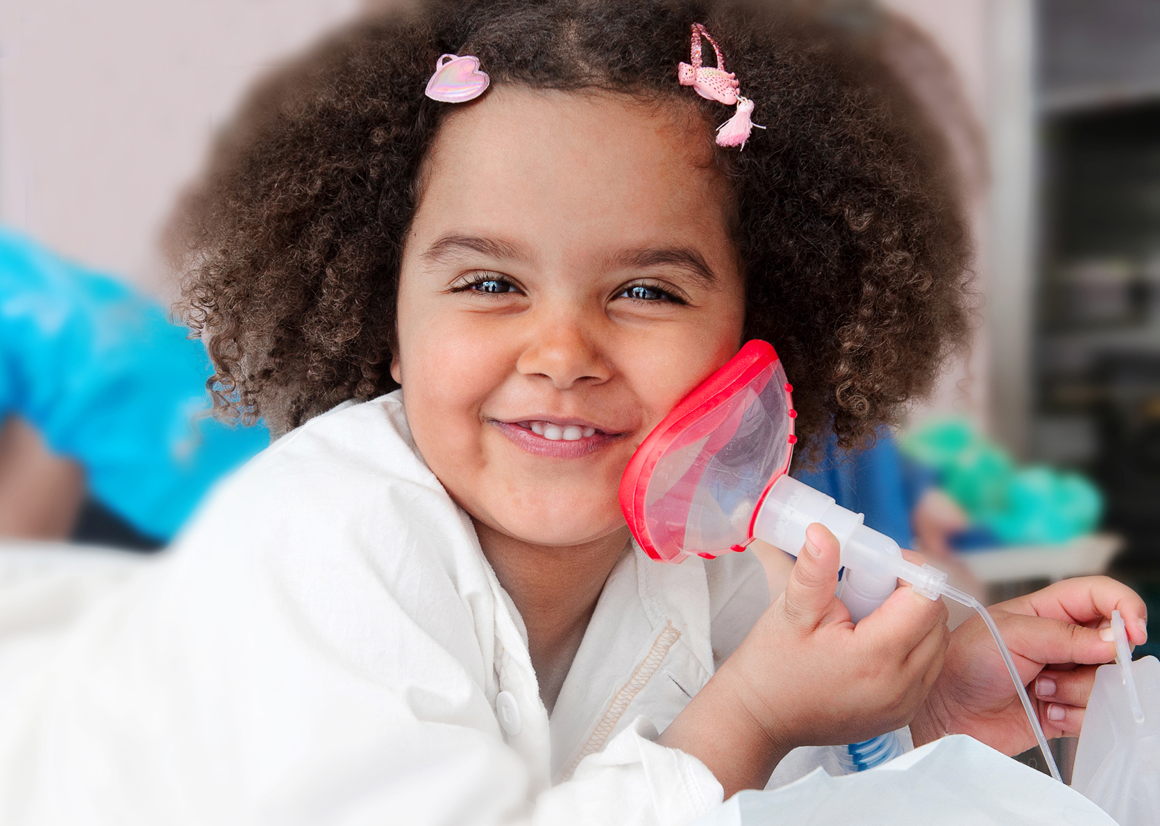 Girl is lying on her stomach on an operating table. She is holding a red oxygen mask.