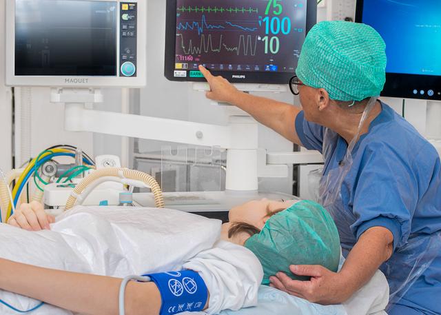 Patient on an operating table. Looking at the monitor together with a nurse.