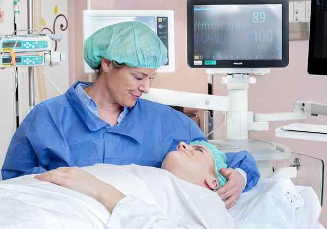 A teenage girl lying on an operating table. Her mother is sitting beside.